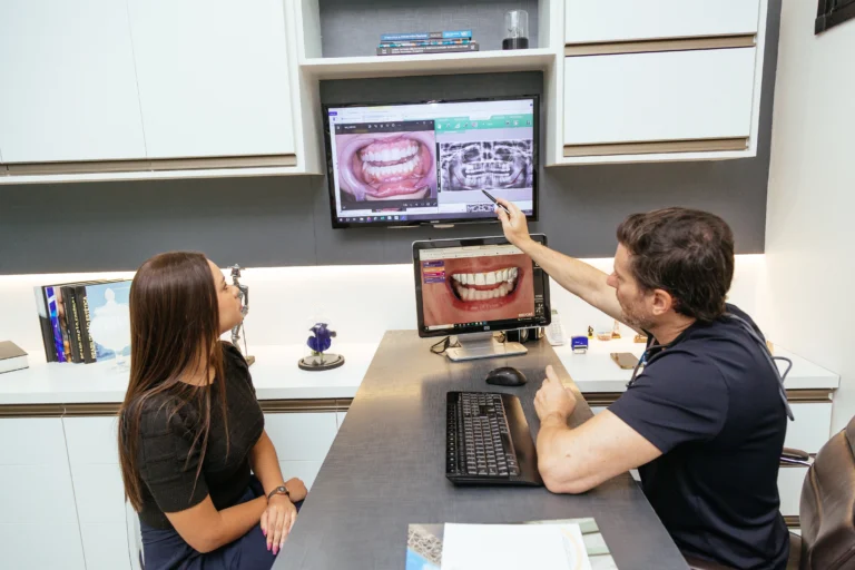 A imagem mostra o Dr. Pedro durante uma consulta apontando para um raio X, explicando o caso para a paciente.